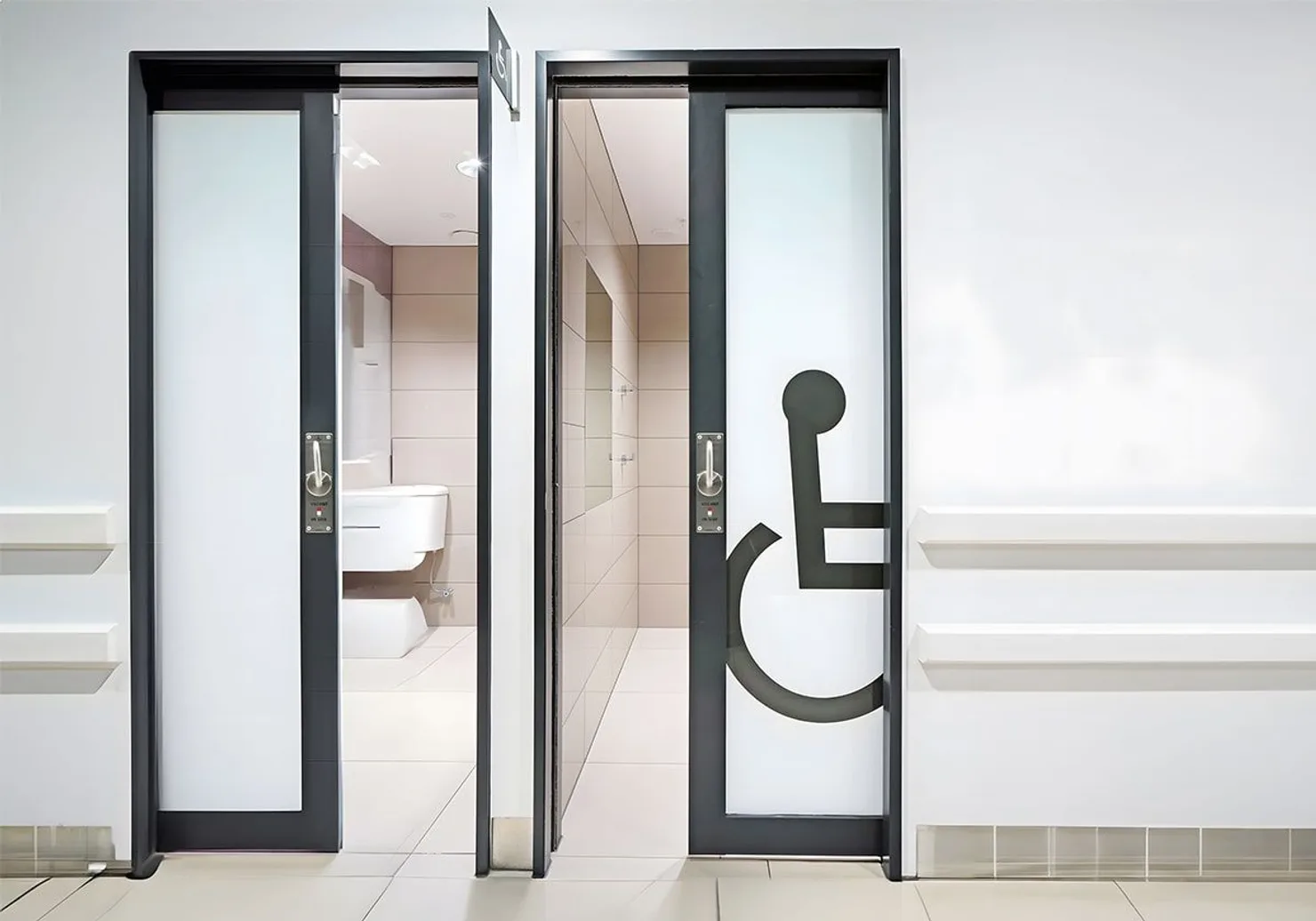 Accessible toilet entrance with automatic sliding doors — the right door displays the international wheelchair accessibility symbol